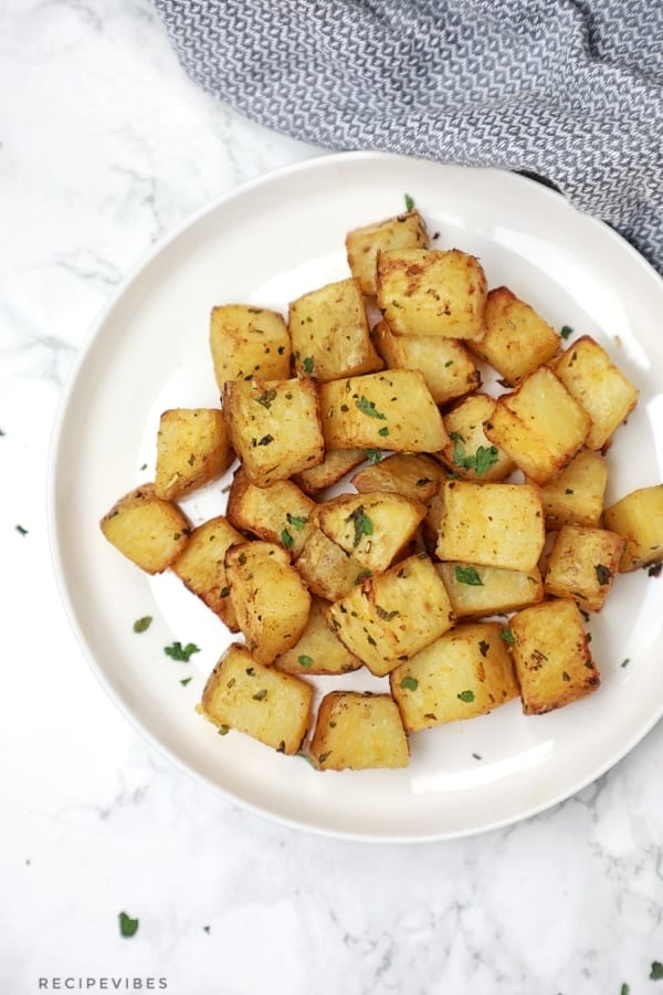 The air fried potatoes served on a plate and garnished with parsley.