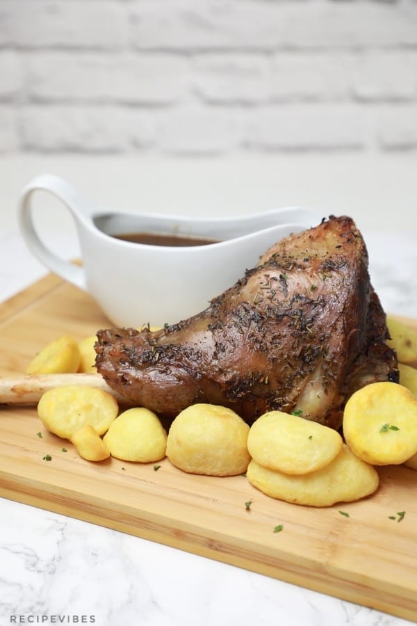 lamb, potatoes, and gravy displayed on a brown board.