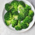 boiled broccoli served on a light blue plate.