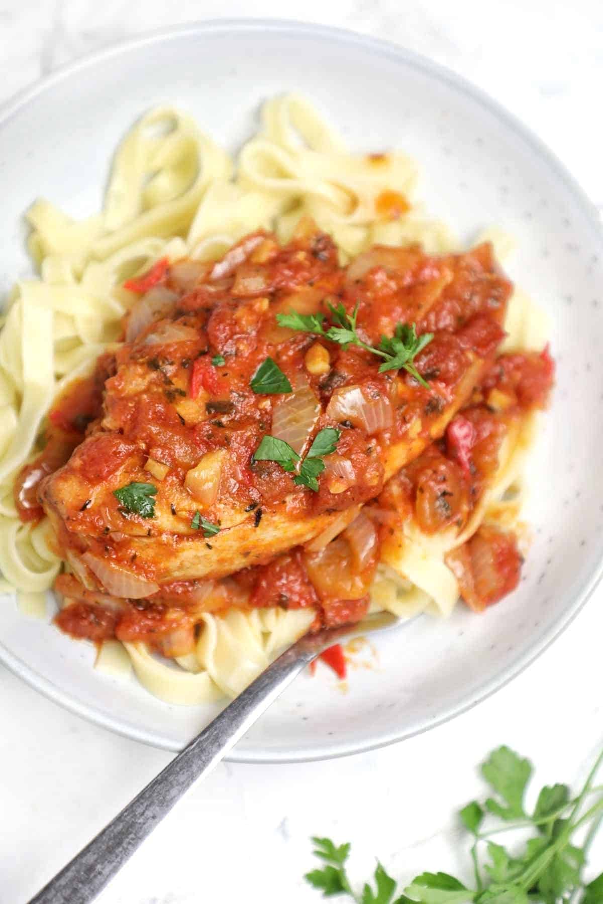 Chicken breast with tomato sauce served on on pasta.