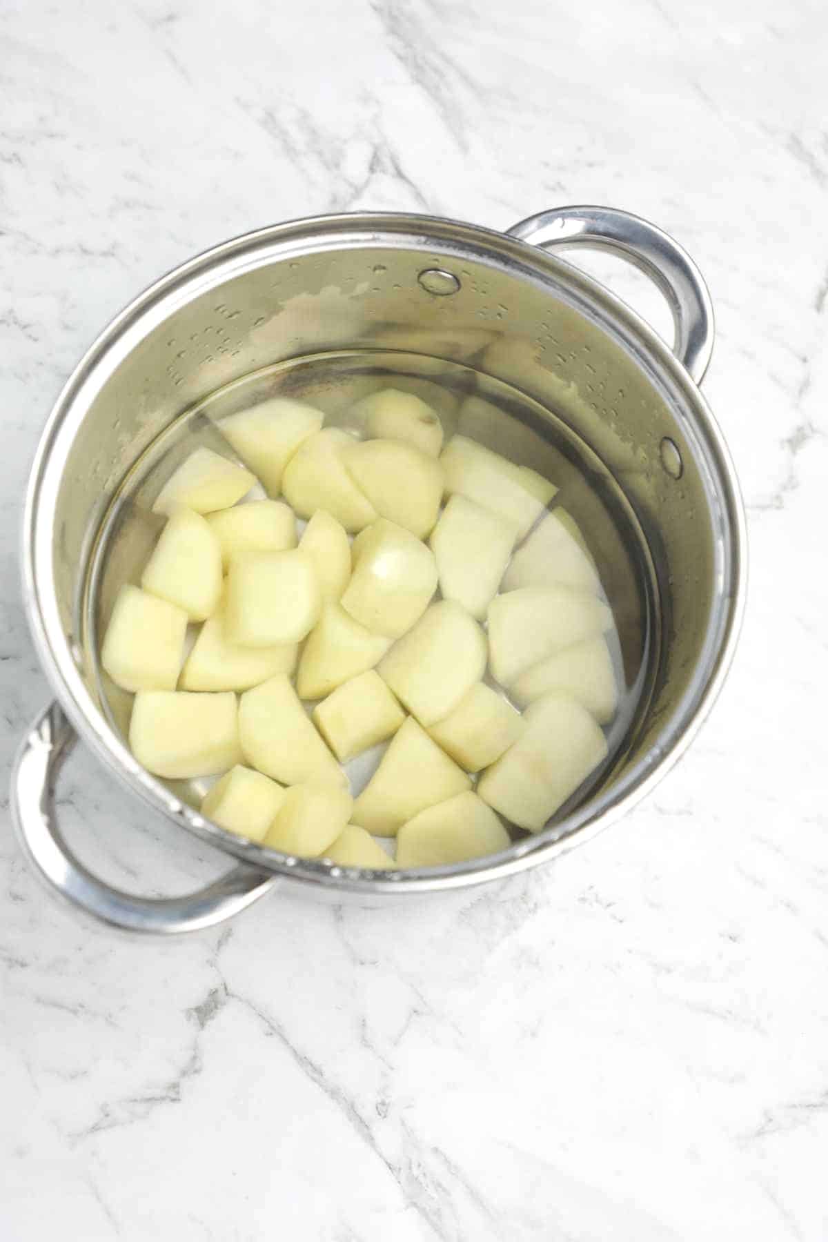 potatoes cvered with water in a pot.