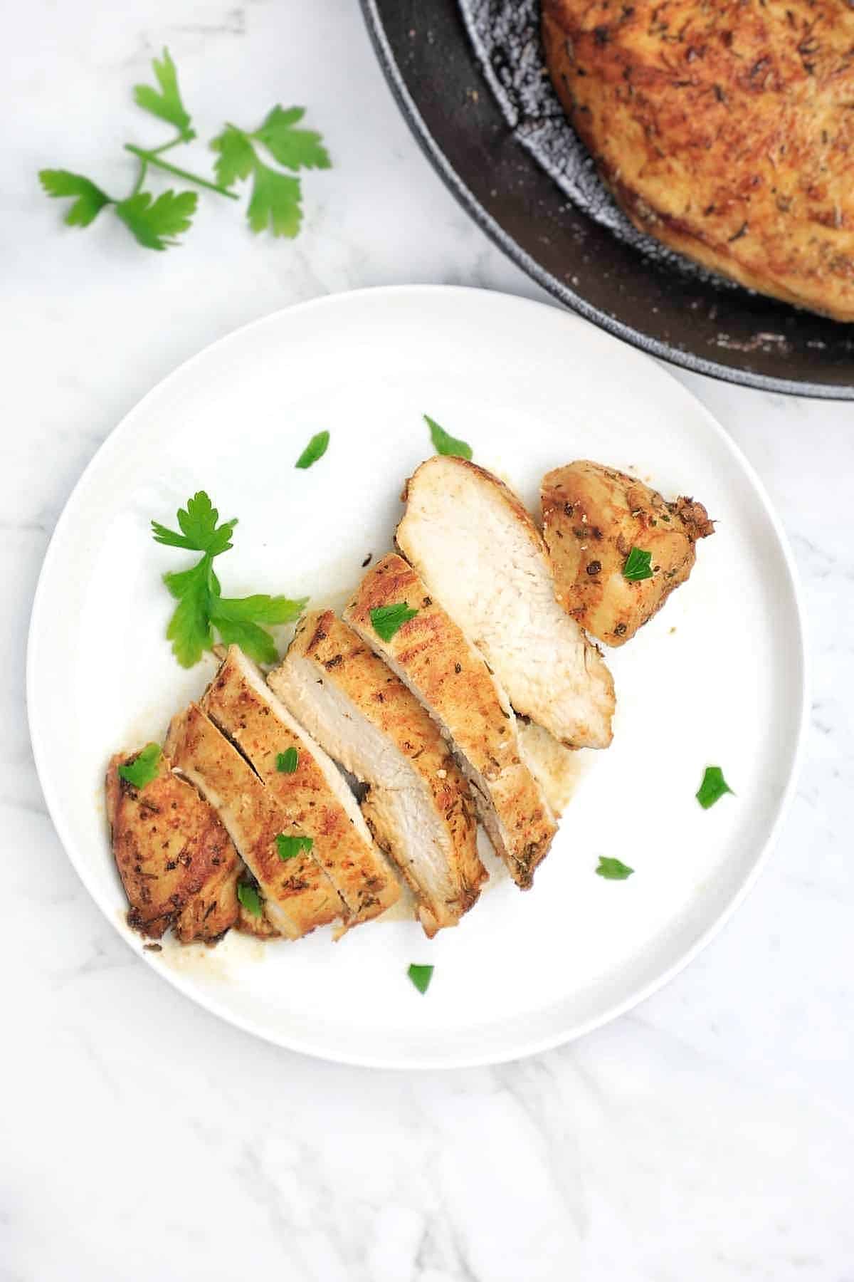 pan fried chicken breast served on a white plate.
