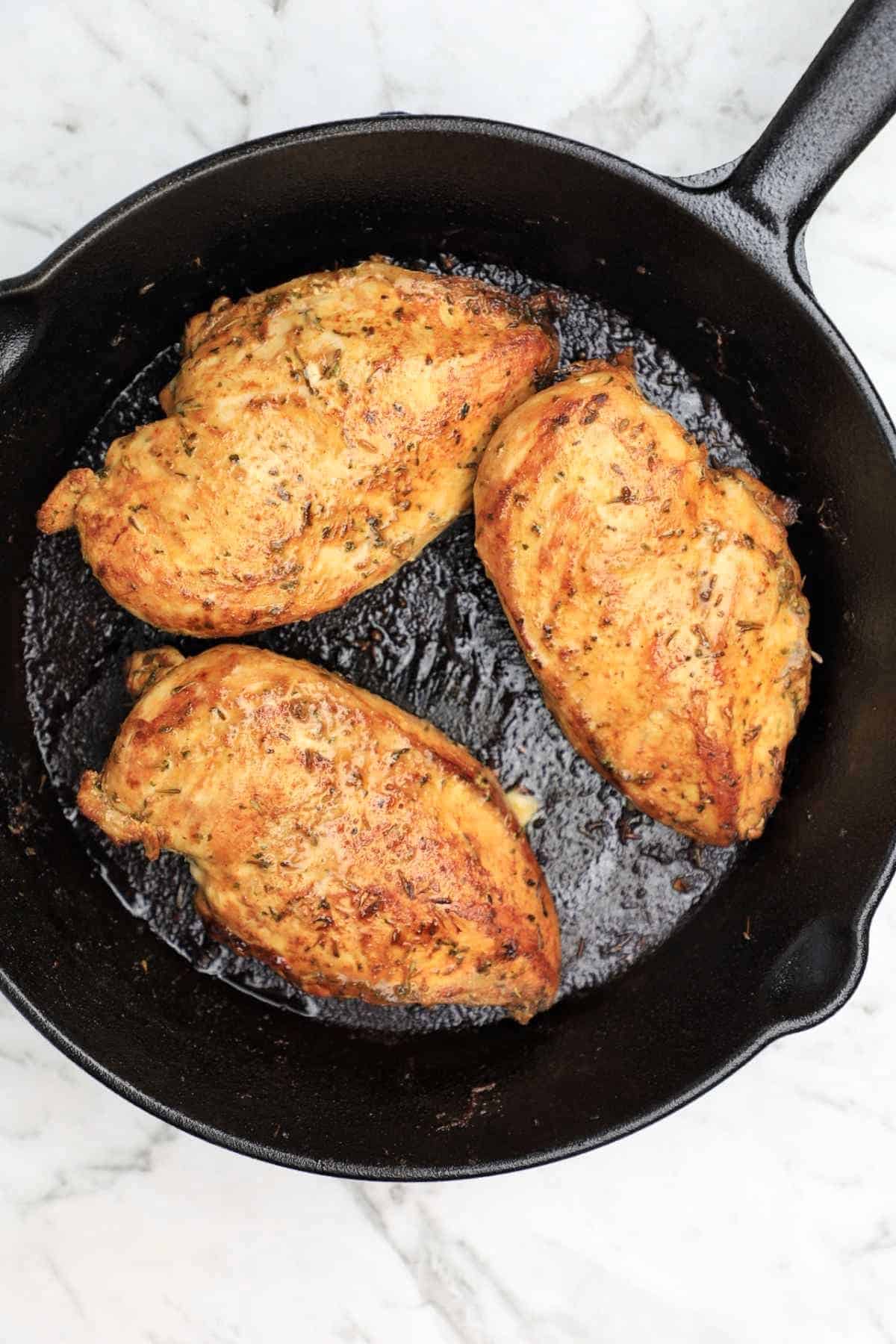 pan fried chicken breasts in a skillet.