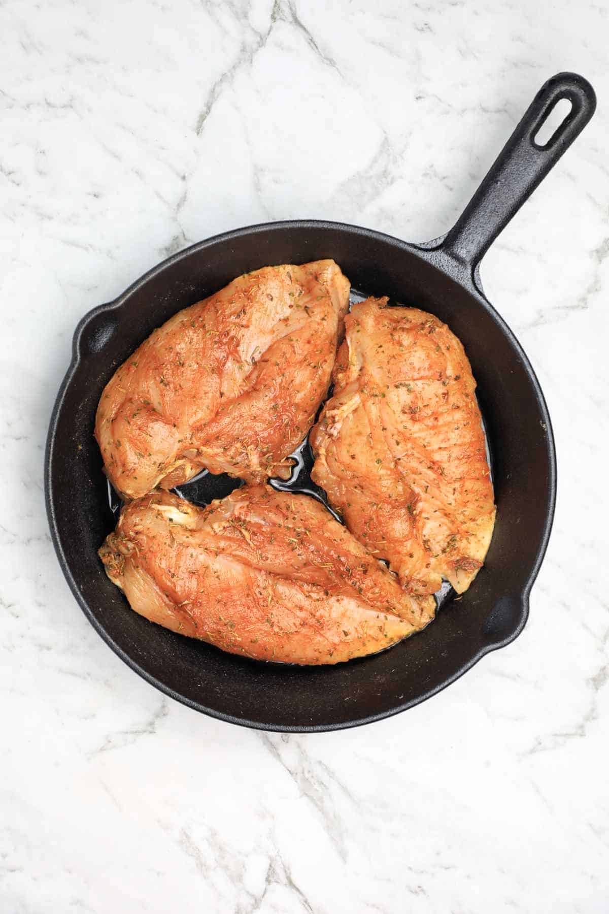 seasoned chicken in a cast iron skillet.