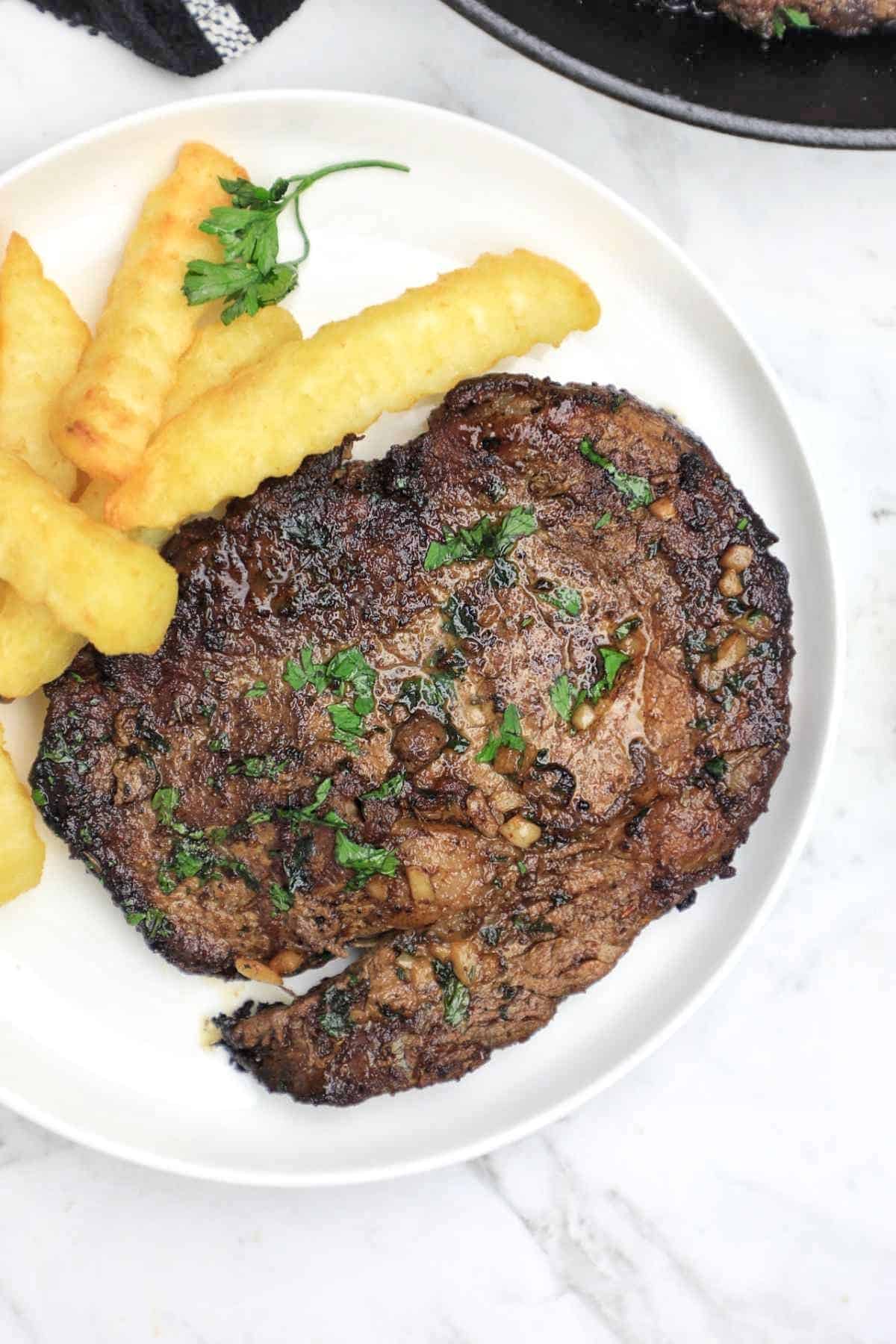 Pan fried steak served with fries and garnished with parsley.