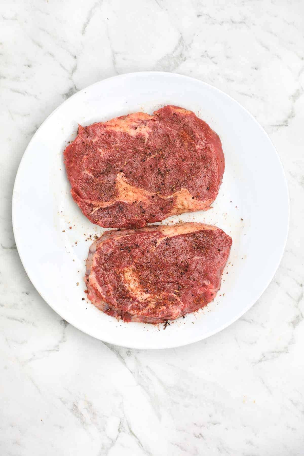 seasoned steaks on a plate.