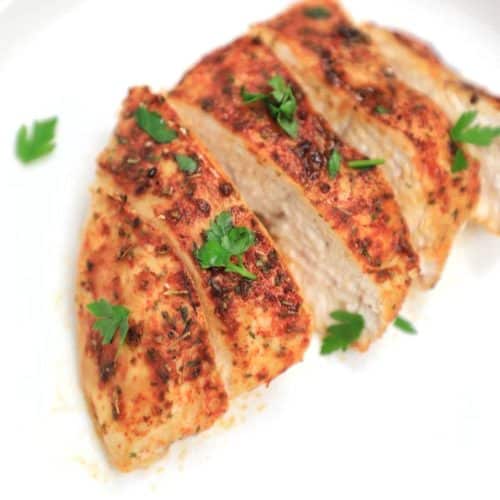 cooked chicken breast served and sliced on a plate.