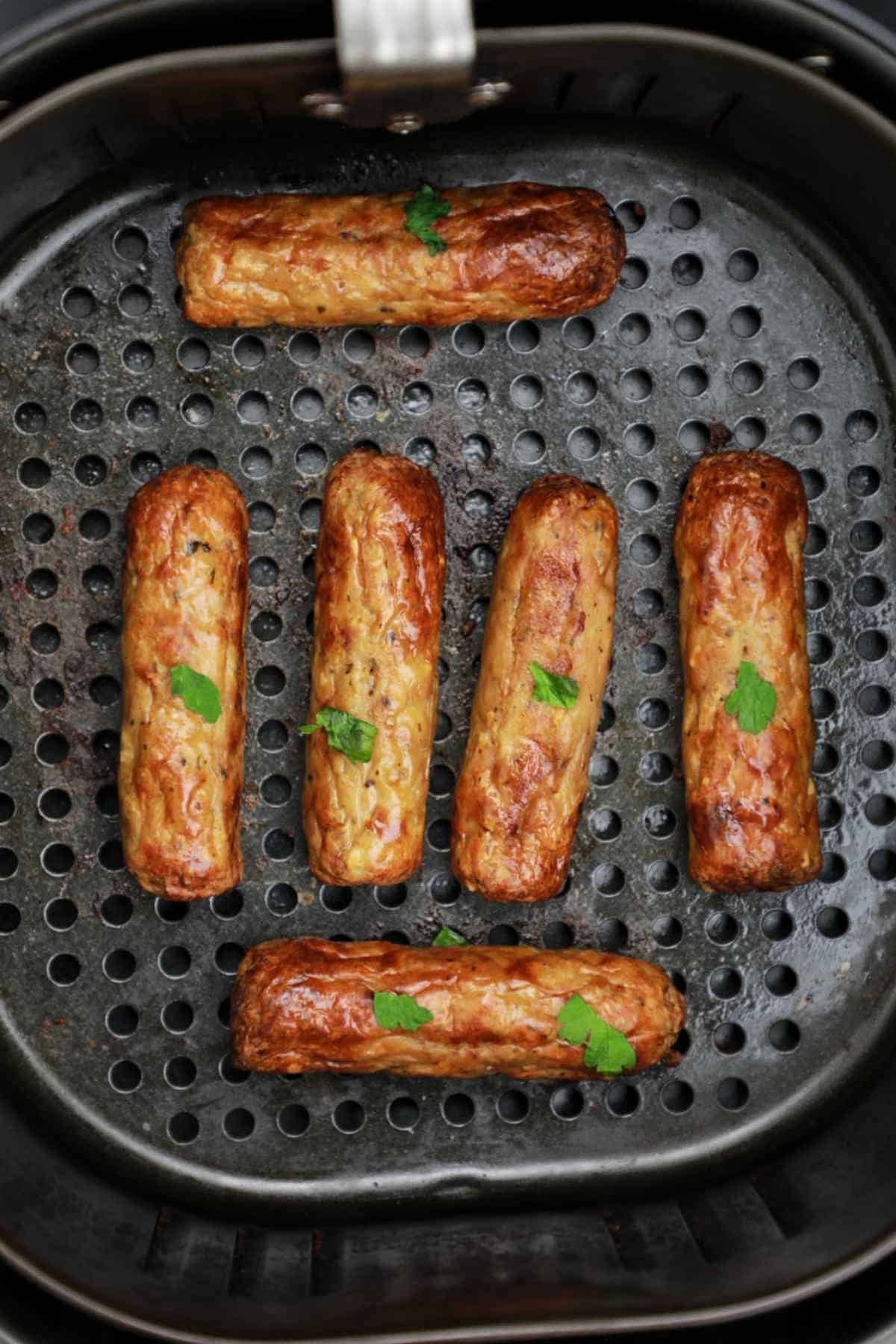 air fried sausages displayed in air fryer basket.