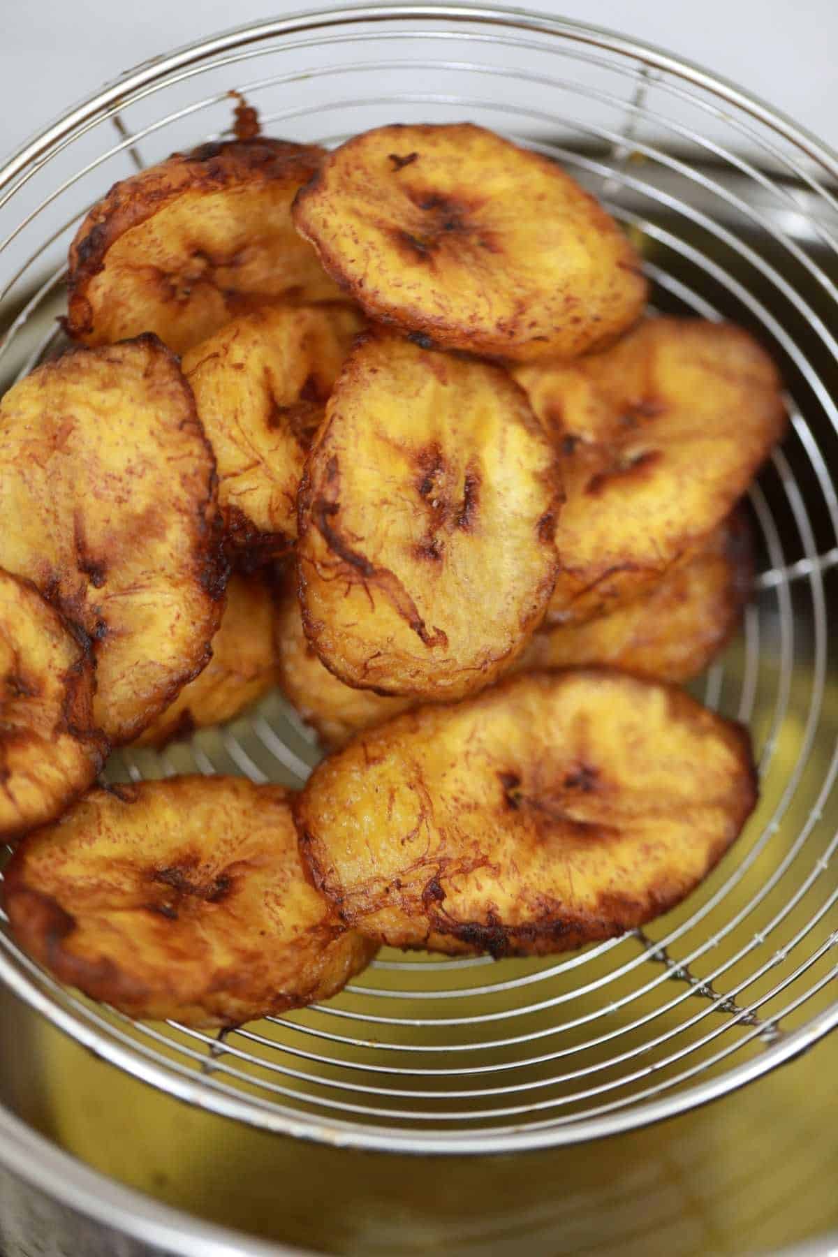 fried sweet plantains in a slotted spoon.