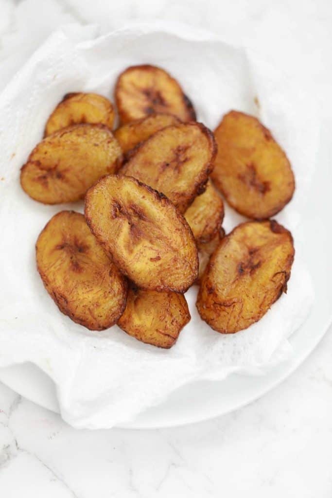 fried plantains served on a paper towel lined plate.