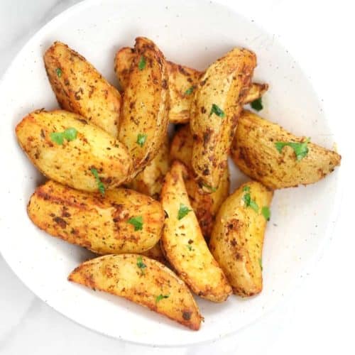 air fryer potato wedges served in a white plate.