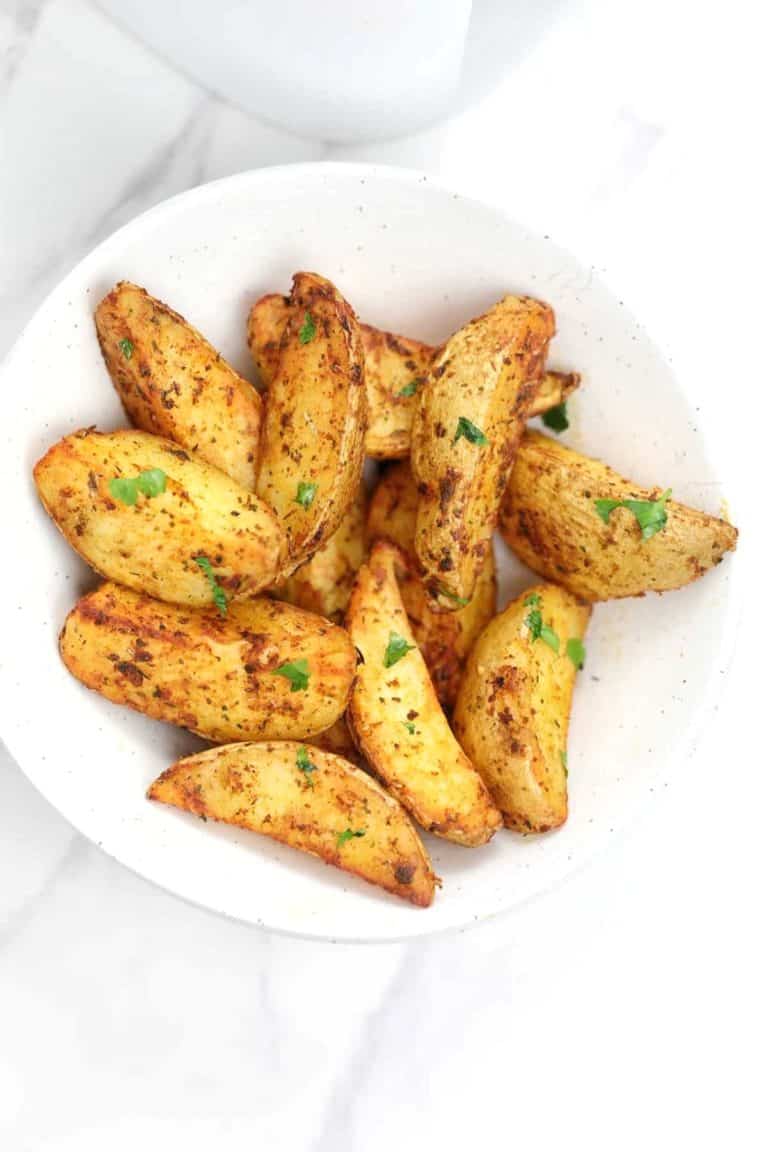 air fryer potato wedges served in a white plate.