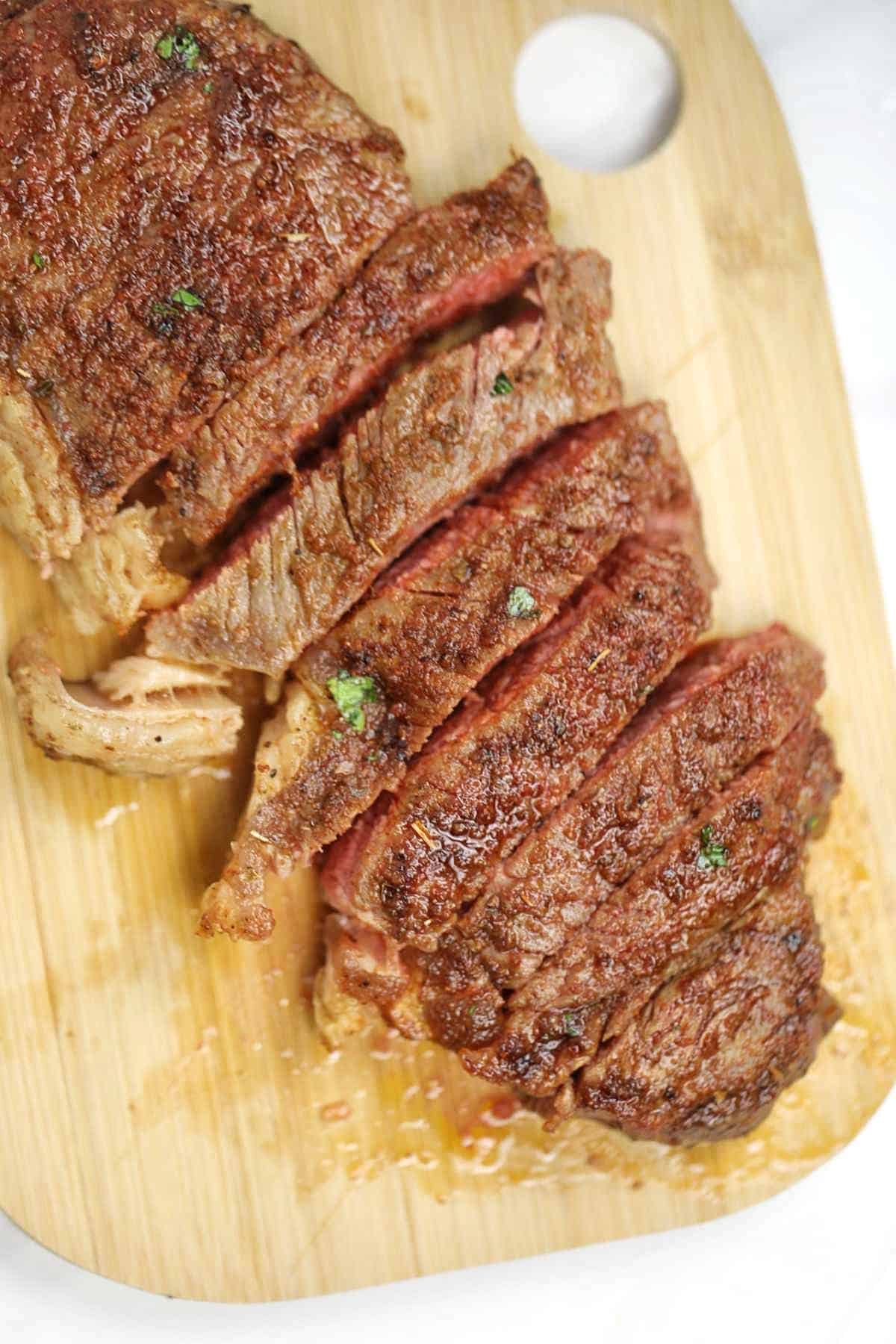 Air fryer sirloin steak cut up on a chopping board.