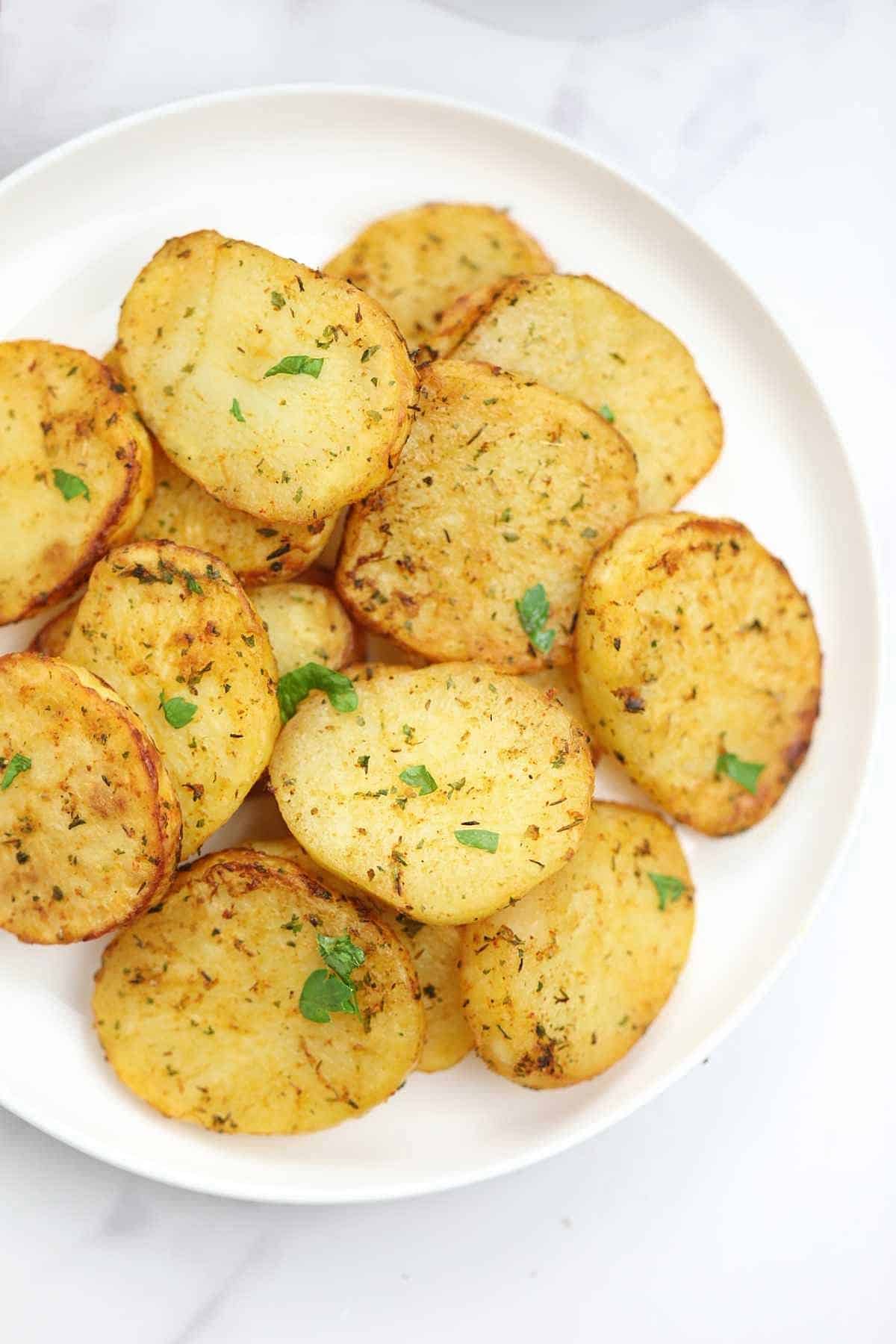 air fryer sliced potatoes on a white plate.