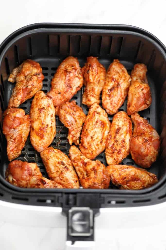 seasoned frozen chicken wings in air fryer basket.