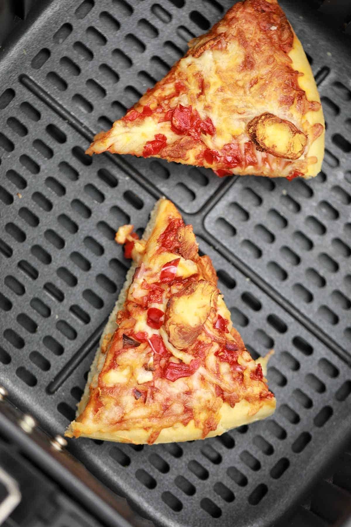 2 slices reheating pizza in air fryer.