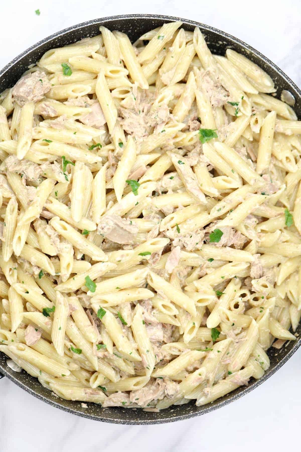 canned tuna pasta in a skillet and garnished with parsley.
