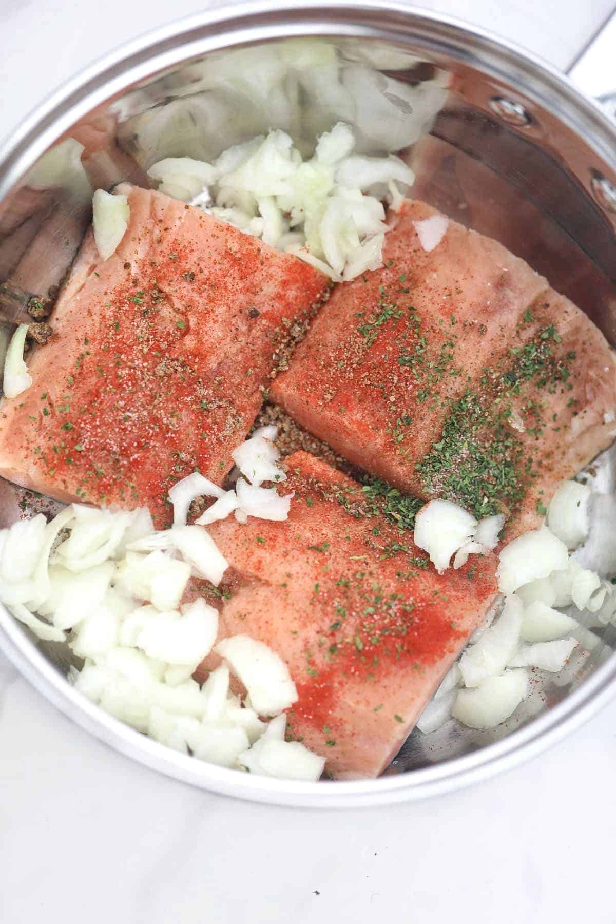 fish fillets and other ingredients in a pot.