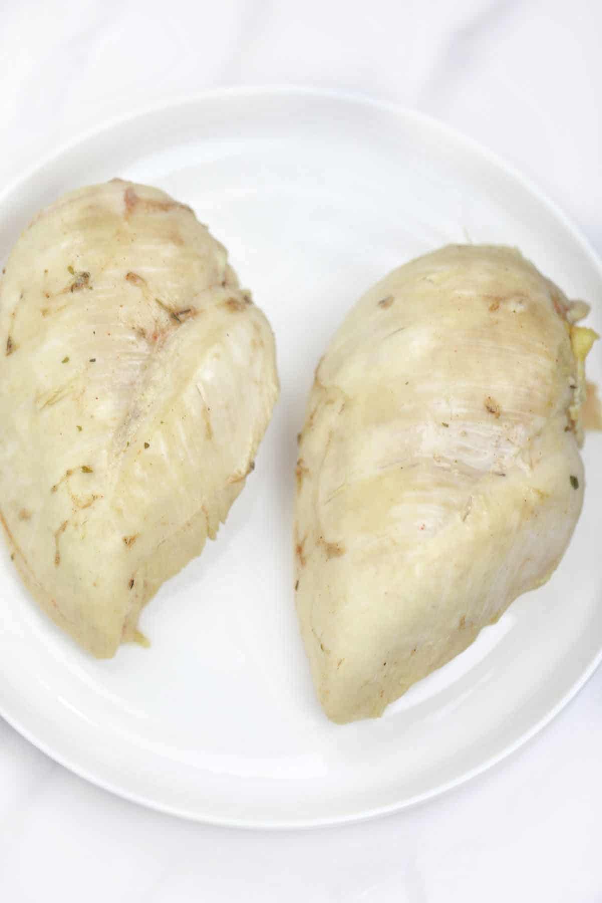 boiled chicken breasts served on a white plate.