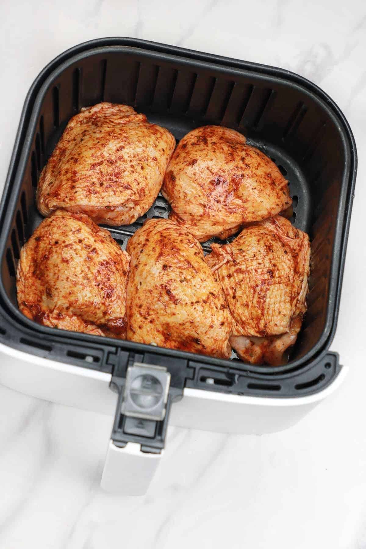 chicken thighs arranged in air fryer.