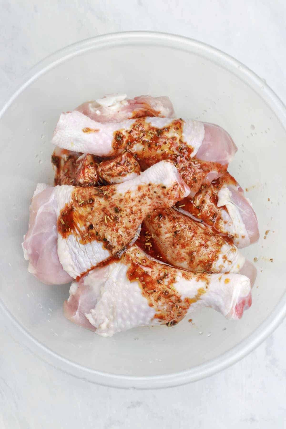 marinade added to drumsticks in a bowl.
