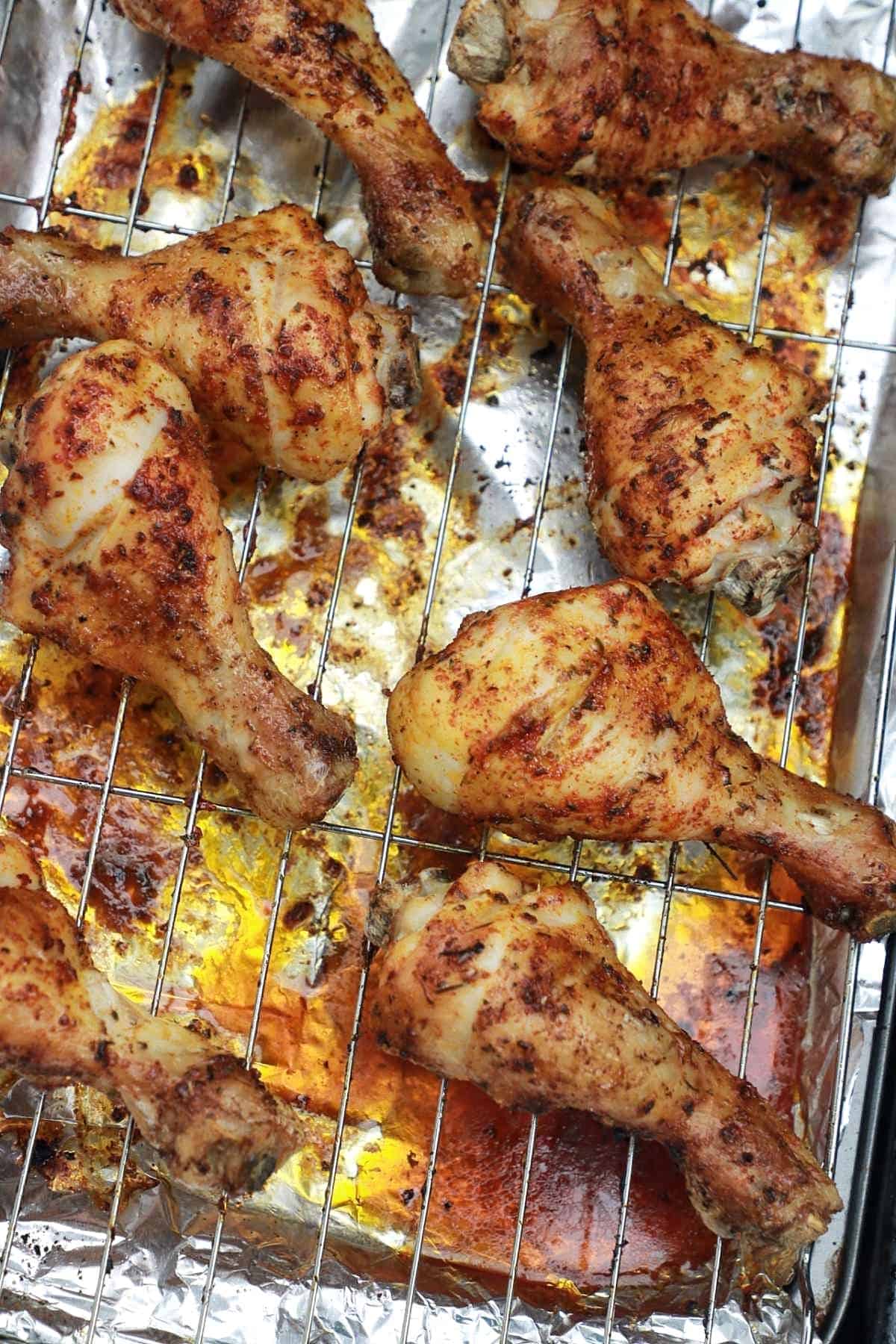 baked chicken drumsticks on baking rack covered tray.