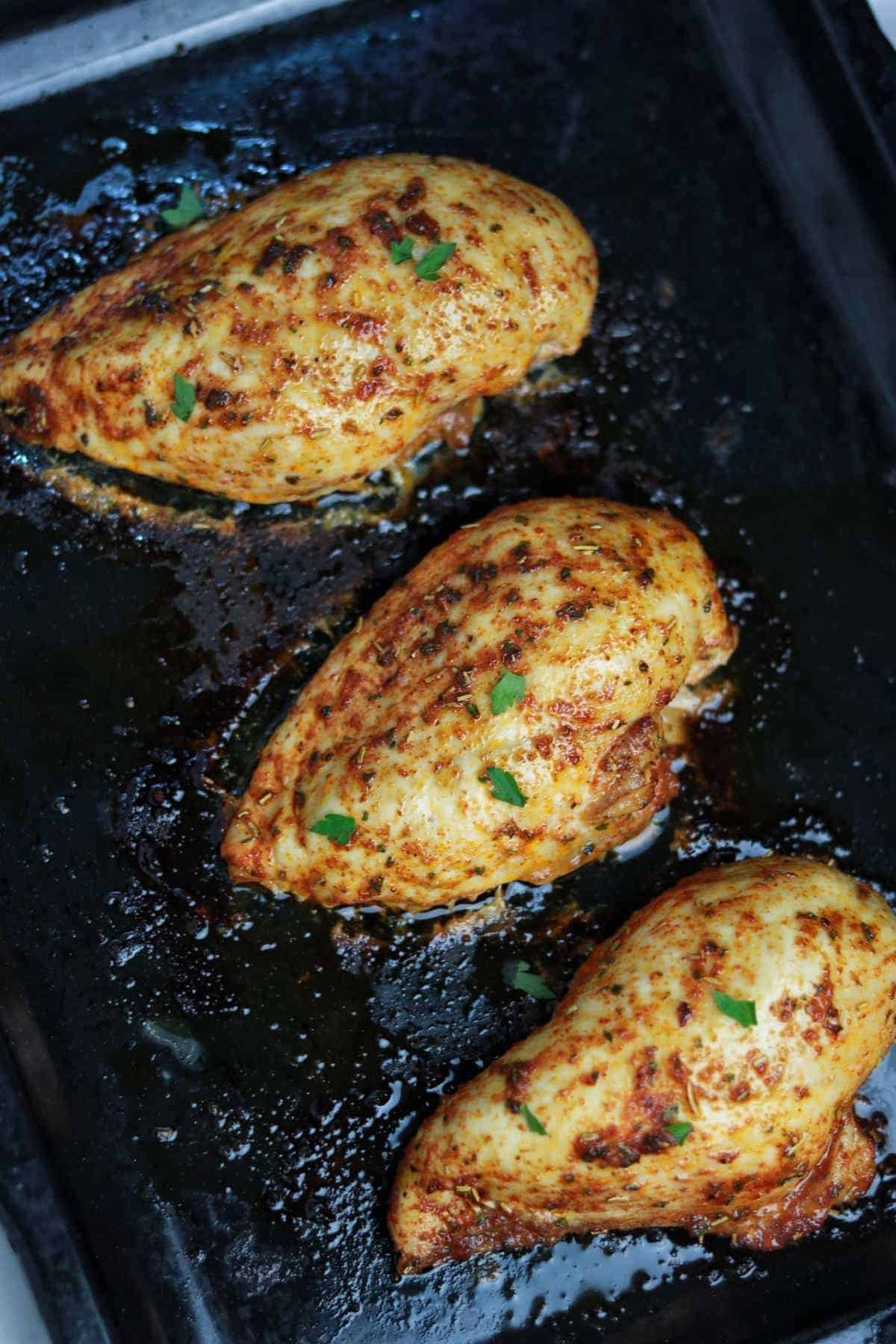 baked frozen chicken breasts on a tray.