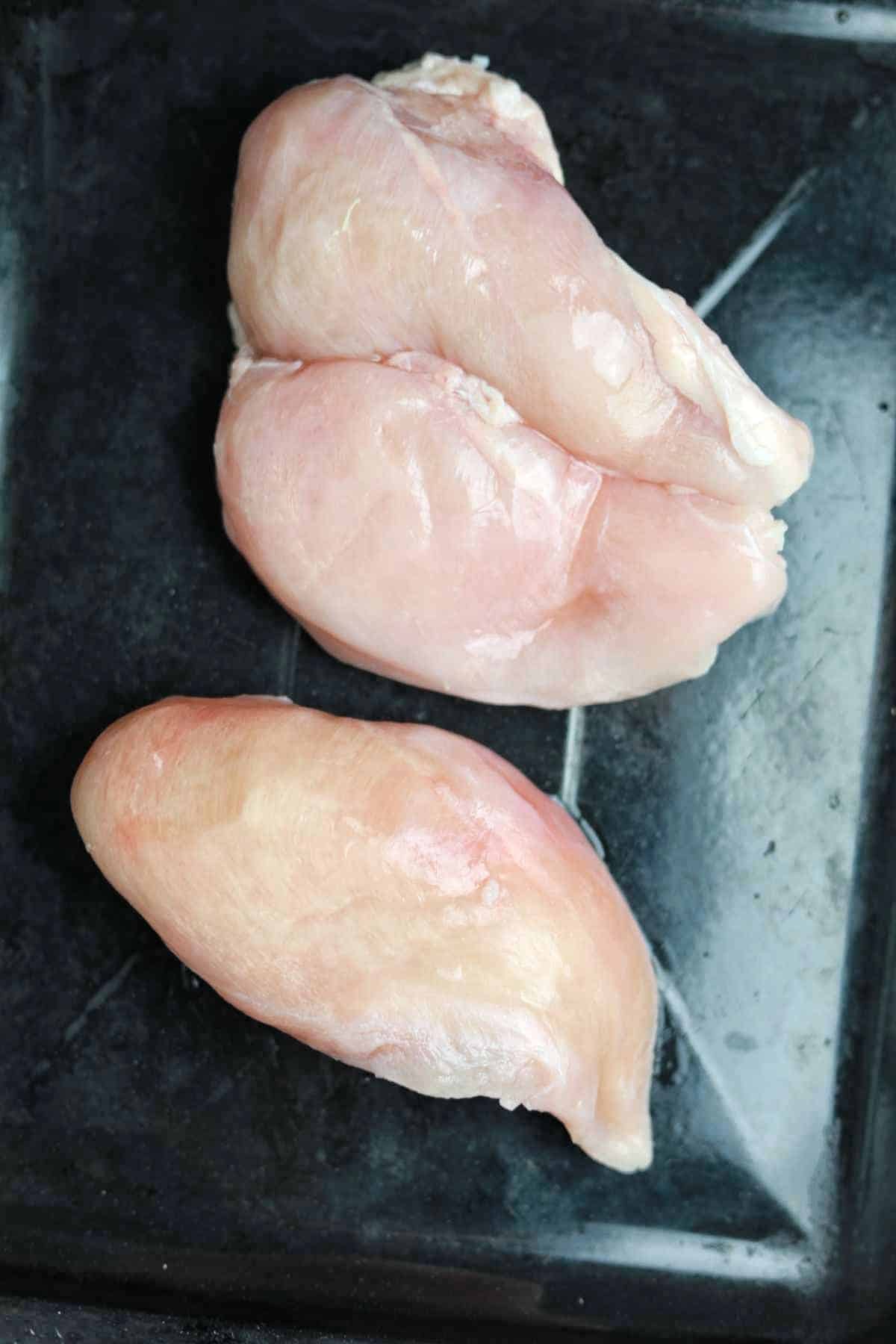 frozen chicken on a baking tray.