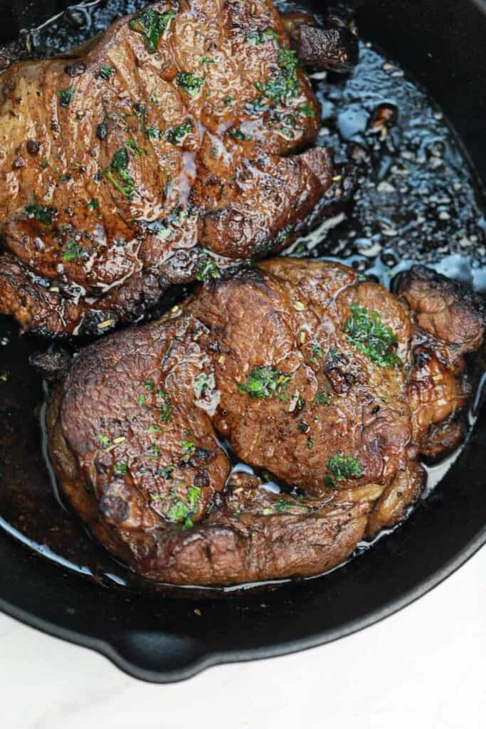 Cooked marinated steaks in a skillet.