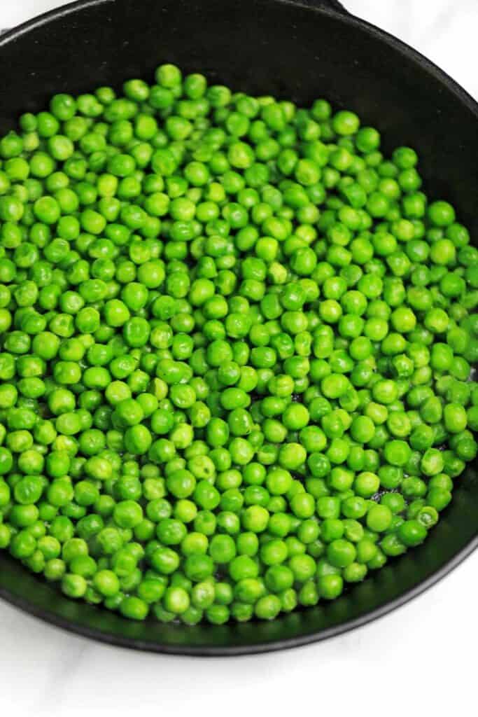 cooked frozen peas in a pan.