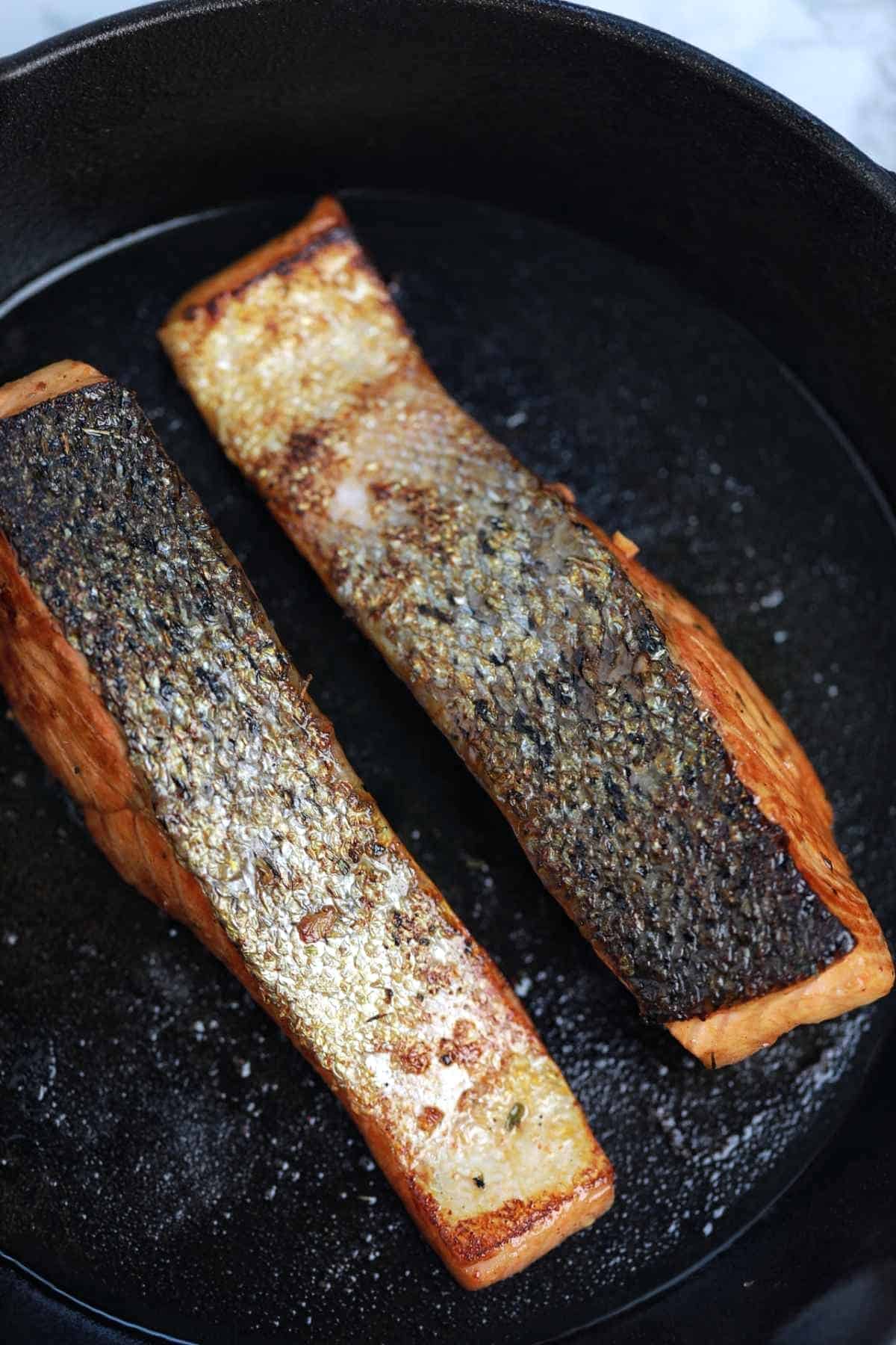 pan fried salmon with skin displayed in a pan.