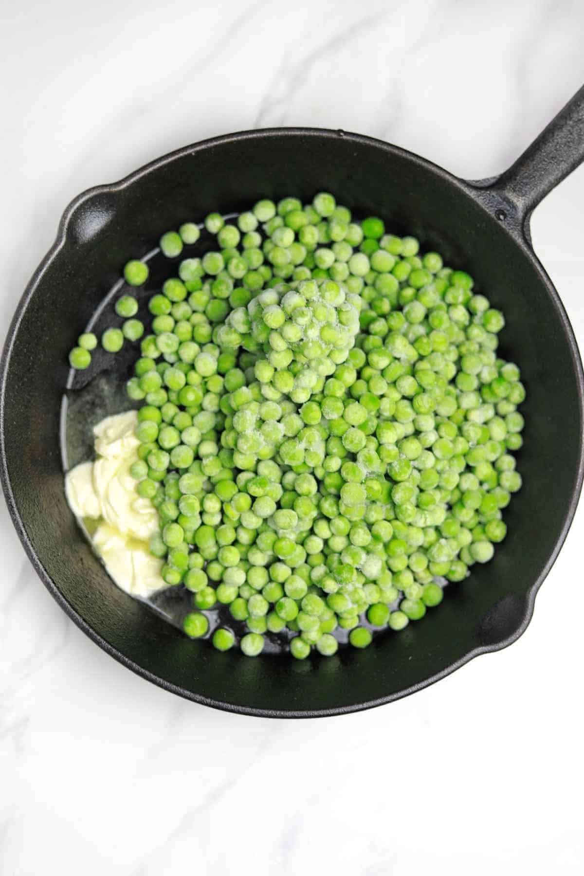 butter and frozen peas added to a skillet.