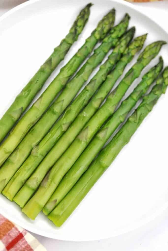 Boiled asparagus on a white plate.