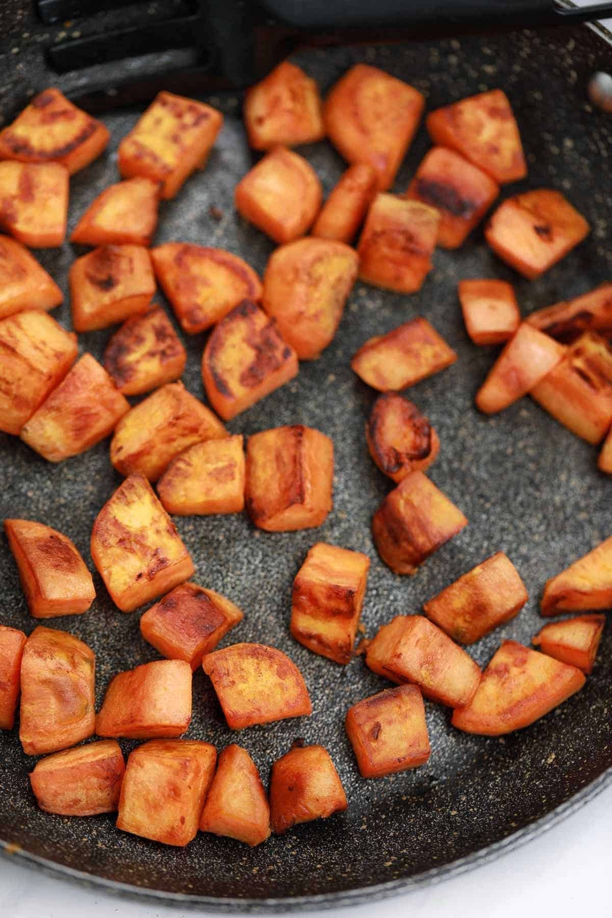 fried sweet potatoes in a frying pan.