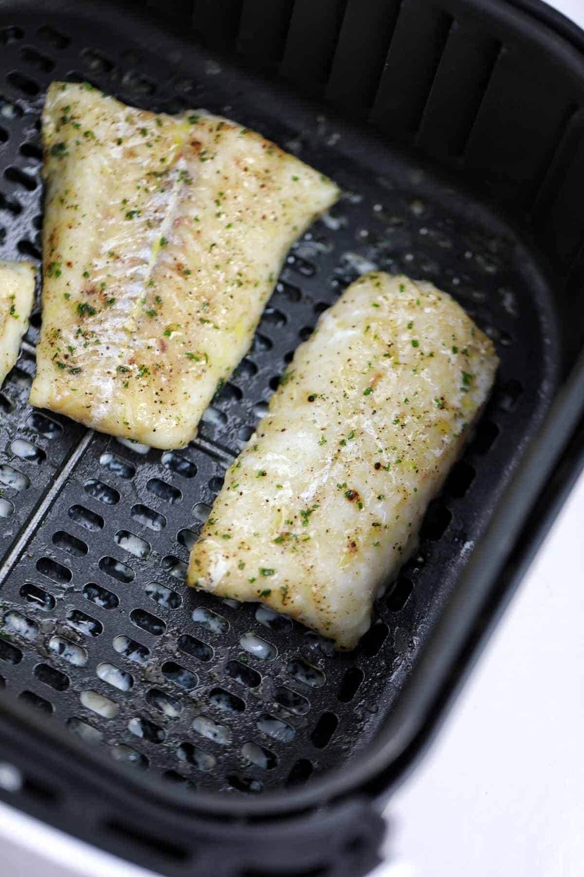 cooked frozen cod fillets in air fryer basket.