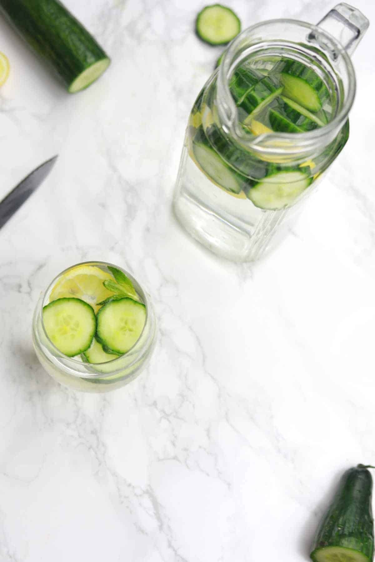 cucumber water in a cup and pitcher.