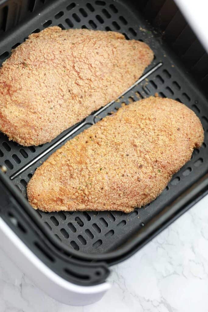 breaded chicken breast fillets arranged in the air fryer basket.
