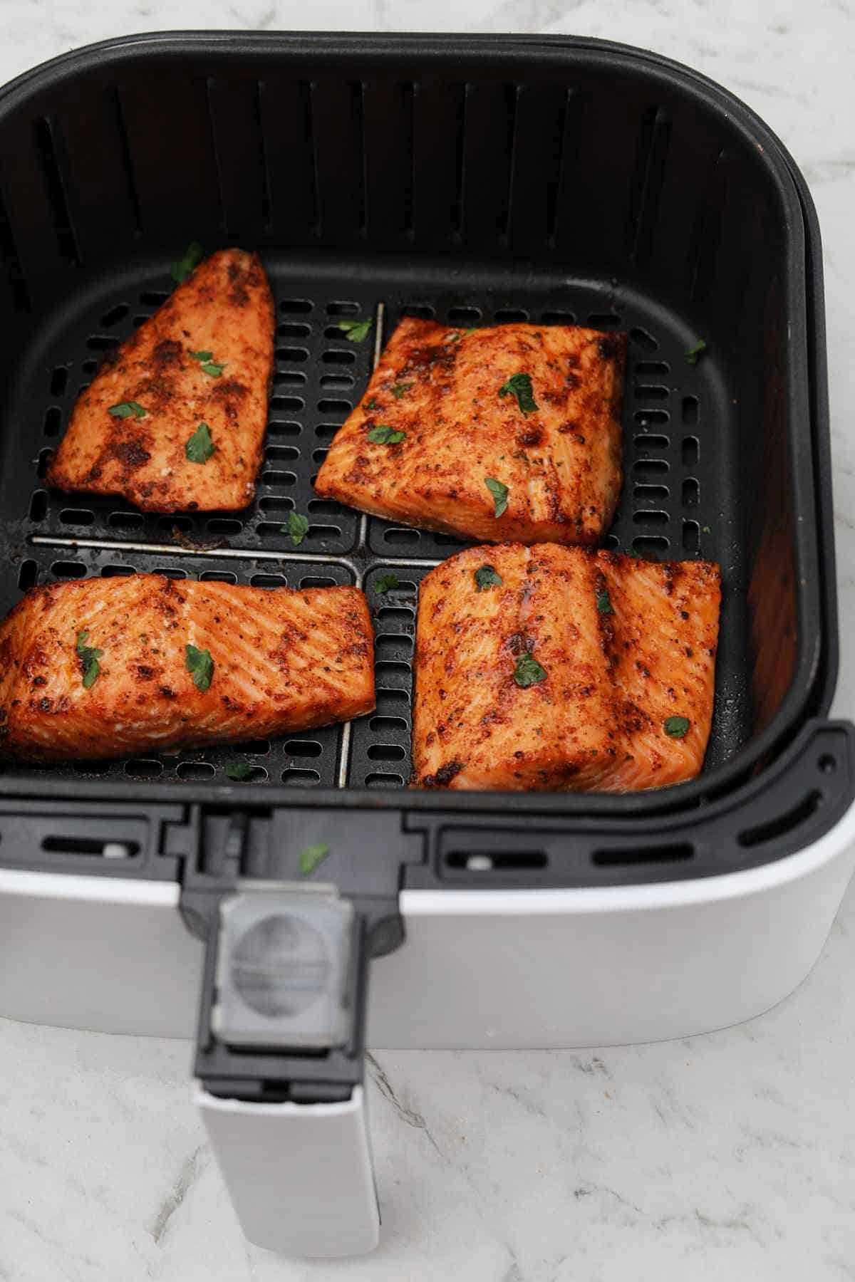 4 cooked trout in air fryer basket.