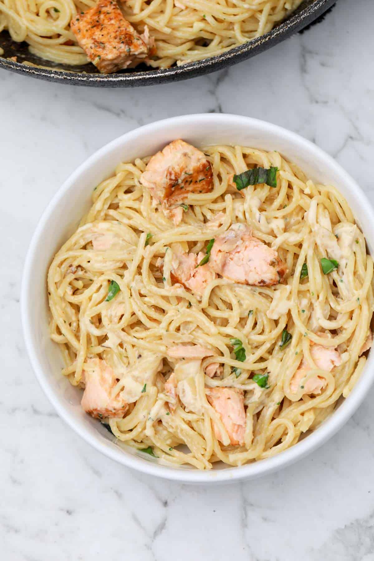 salmon pasta served on a white plate.