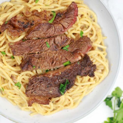 steak pasta served on a plate.
