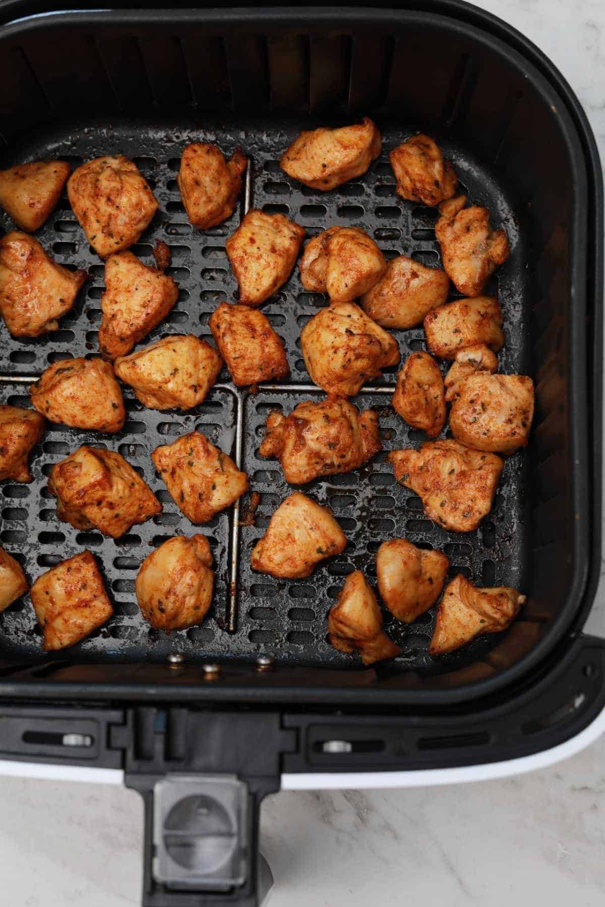 chicken chunks in air fryer basket.