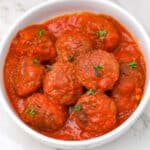 meatball sauce served in a white bowl and garnished with parsley.