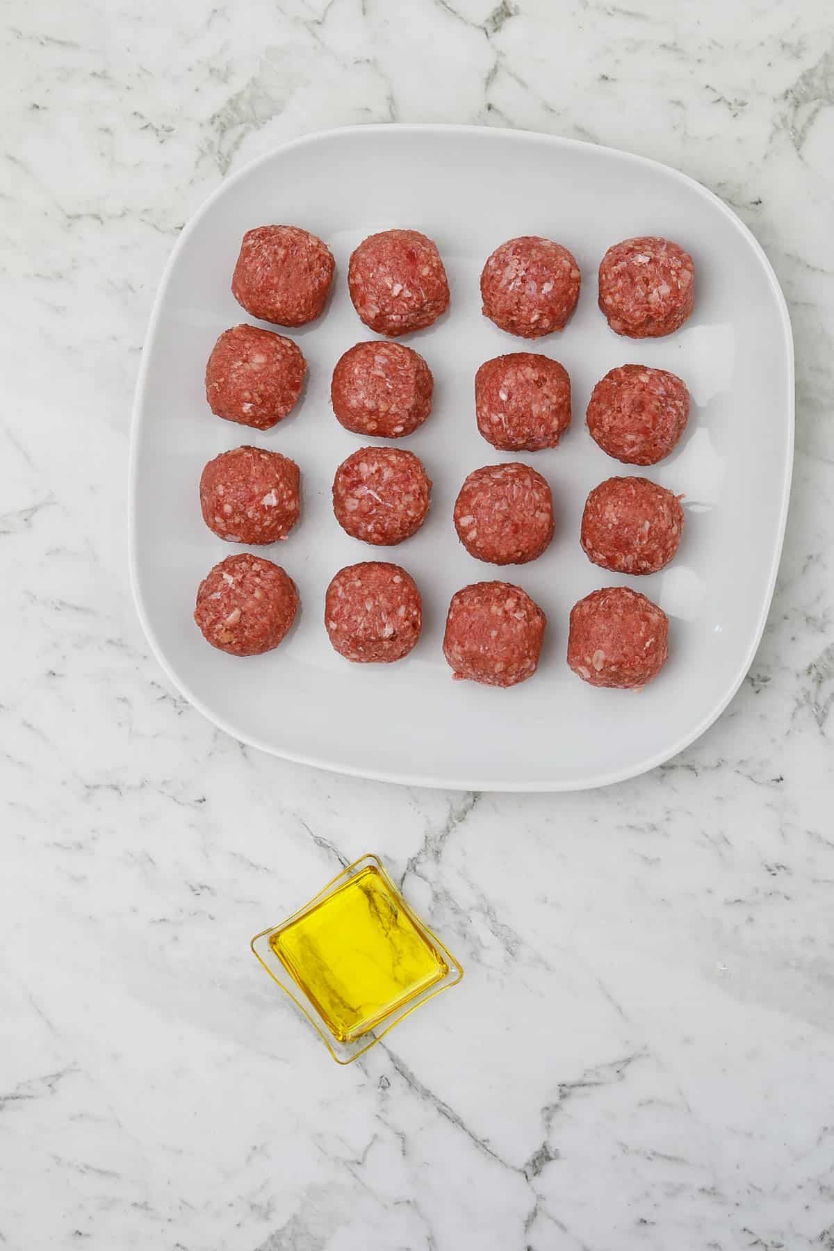 meatballs in a plate and oil in a small bowl.