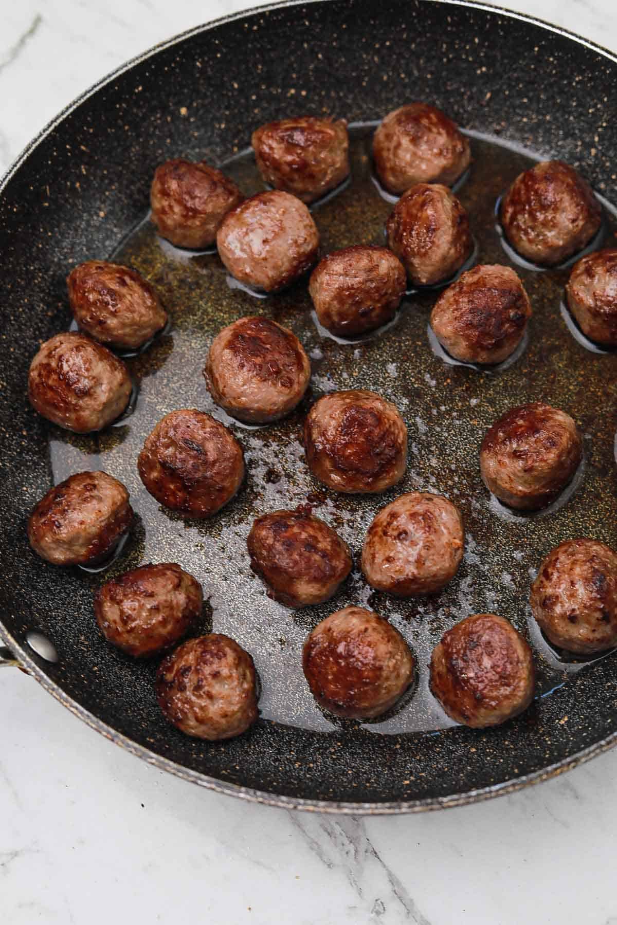 Fried meatballs in a skillet.