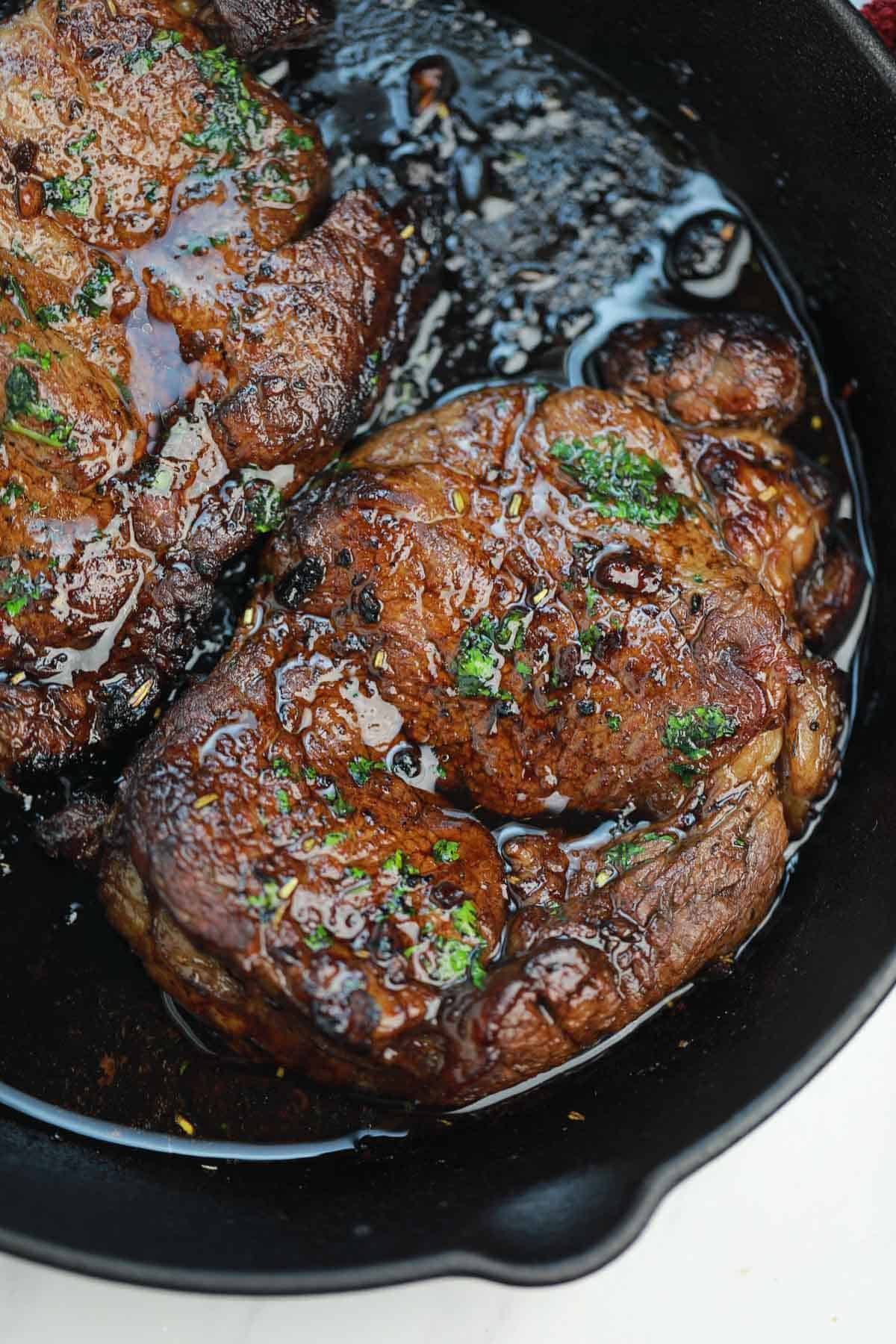 cooked steak in a skillet picture for what goes well with steak (steak side dishes) post.