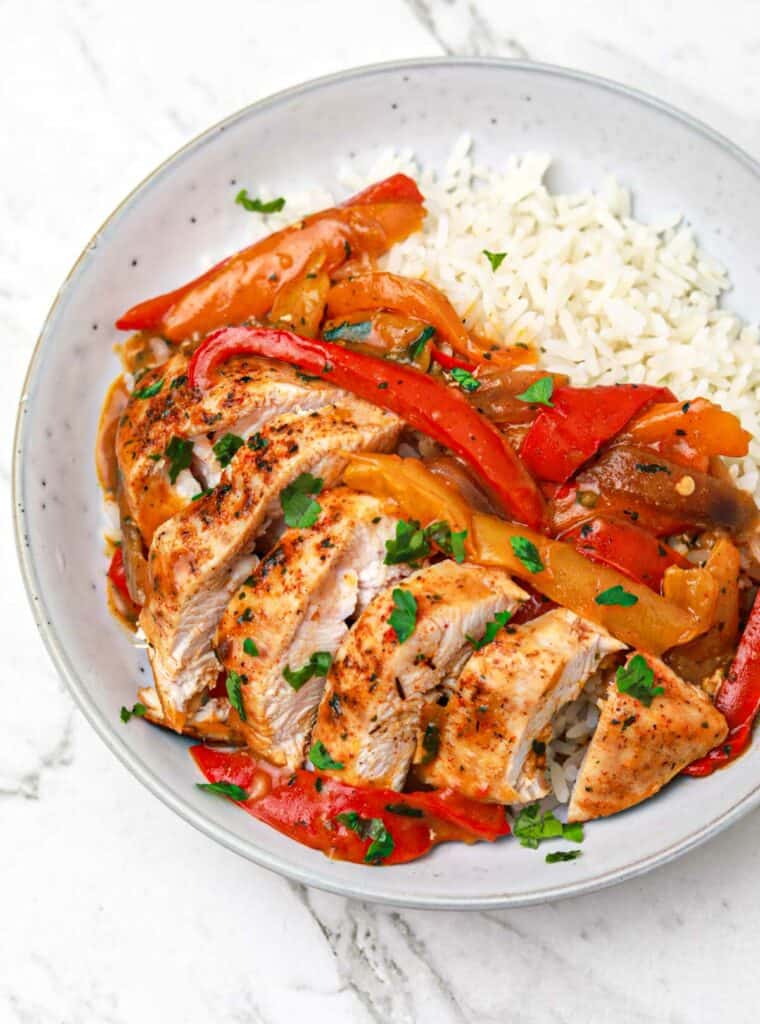 chicken and bell peppers with onions served on rice.
