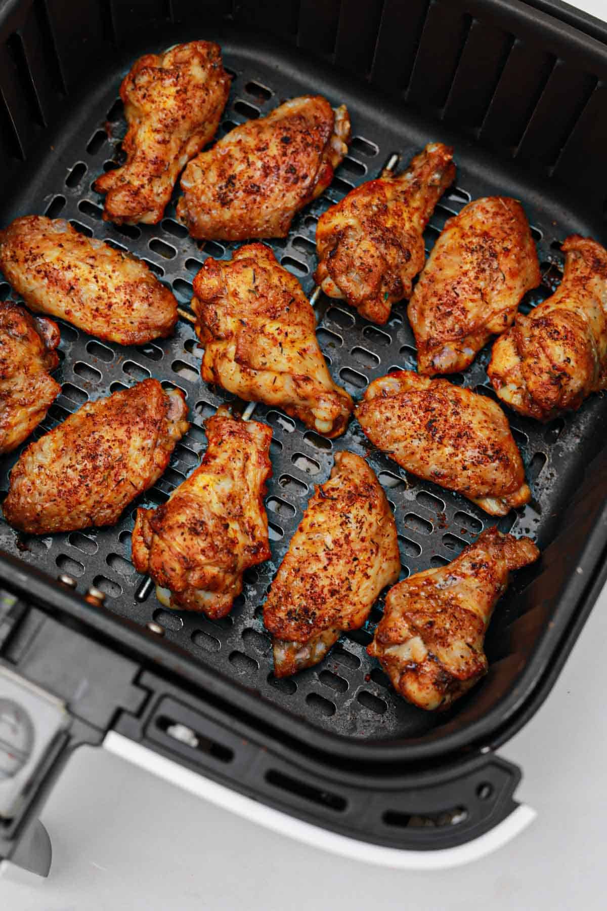 Cooked chicken wings in air fryer shown in the air fryer.