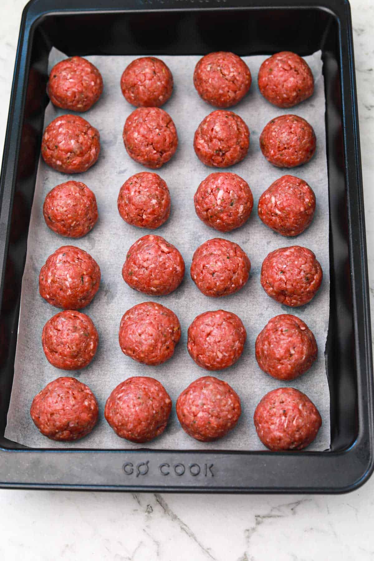 meatballs arranged on a baking paper lined tray.