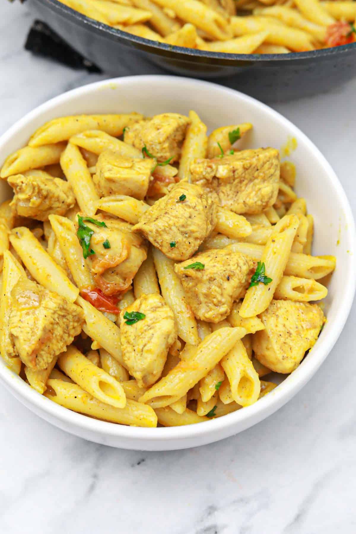curry chicken pasta served on a white plate.