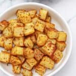 baked diced potatoes served in a white bowl.